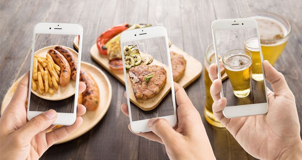 friends-using-smartphones-to-take-photos-of-sausage-and-pork-chop-and-beer-1200x0-copy-620x329